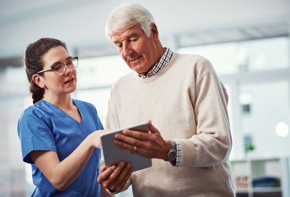 Could you show me. a young female nurse and her senior patient looking at a tablet in the old age home.