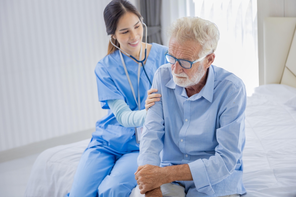 Hospice nurse is using stethoscope on Caucasian man in bed for d