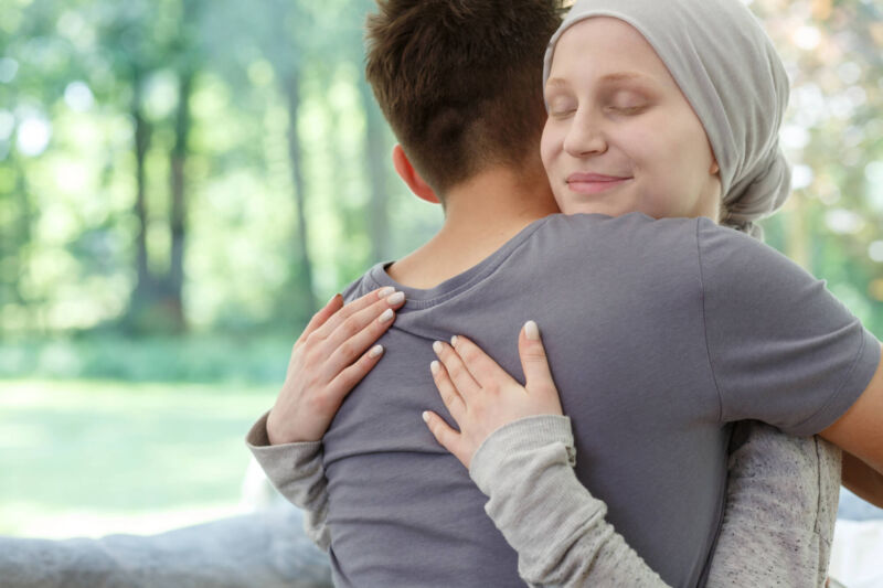 Young woman with a headscarf peacefully embracing a loved one in a sunlit setting, symbolizing emotional support during stage 4 breast cancer hospice