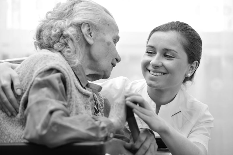 A compassionalte nurse providing care to an elderly woman in the final stages of dementia